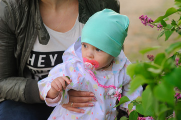 Happy mother and daughter in the garden of blooming lilacs