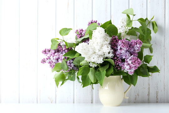 Blooming lilac flowers in the vase on wall paneling background