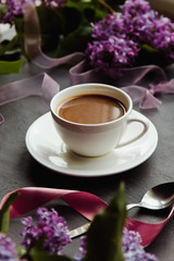 Beautiful background with a Cup of hot coffee with lilacs