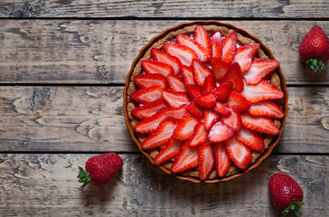 Strawberry tart with cream traditional summer sweet pastry fruit dessert on vintage wooden table...