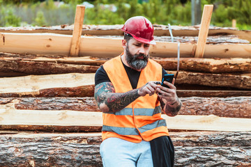 Worker in overalls and with a tattoo are checking the quality of materials and other inspections, makes recording on your mobile phone