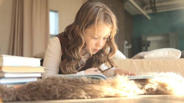 школьница читает книгу лежа на кровати