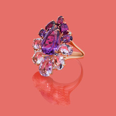 Jewelry gold ring with pink and purple topazes on red background