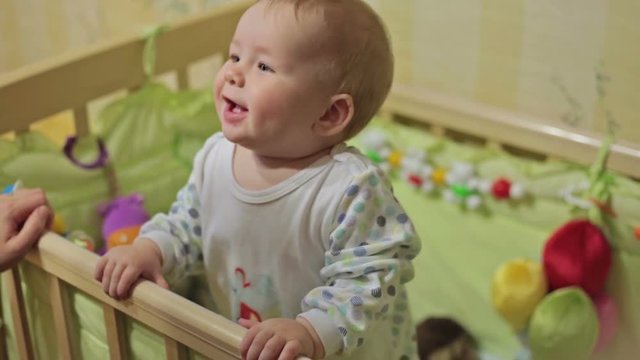 Cute baby boy standing in crib