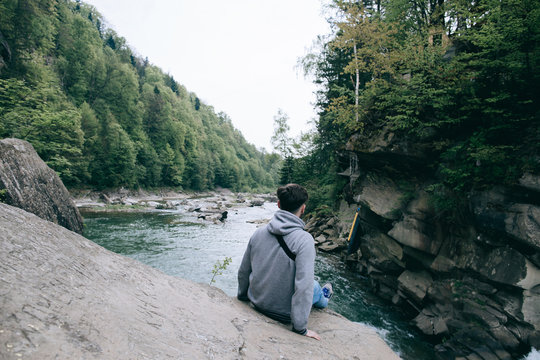 lonely man sitting and relax on a rock waterfall mountain river