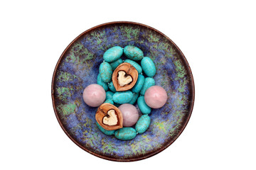 половинки грецкого ореха в форме сердца рядом с шарами из розового кварца, бусами бирюзы в керамической голубой чаше