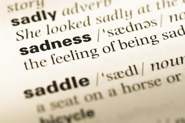 Fototapeta premium Close up of old English dictionary page with word sadness