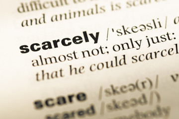 Obraz premium Close up of old English dictionary page with word scarcely