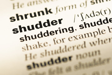Close up of old English dictionary page with word shudder