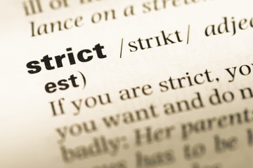 Close up of old English dictionary page with word strict