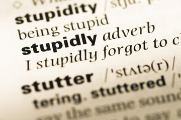 Obraz premium Close up of old English dictionary page with word stupidly