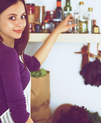 Young woman standing in her kitchen near desk