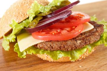 Traditional American cheeseburger. Meat, bun and vegetables close up
