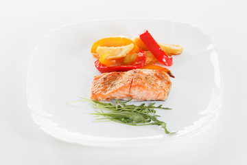 Grilled salmon fillet with vegetables, spices and arugula on a plate