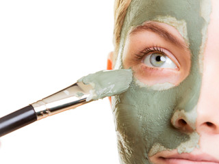 Woman applying with brush clay mud mask her face