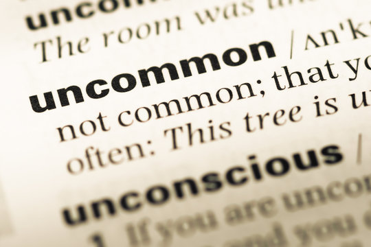 Close up of old English dictionary page with word uncommon