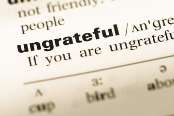 Close up of old English dictionary page with word ungrateful