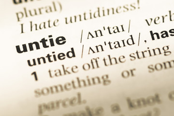 Fototapeta premium Close up of old English dictionary page with word untie