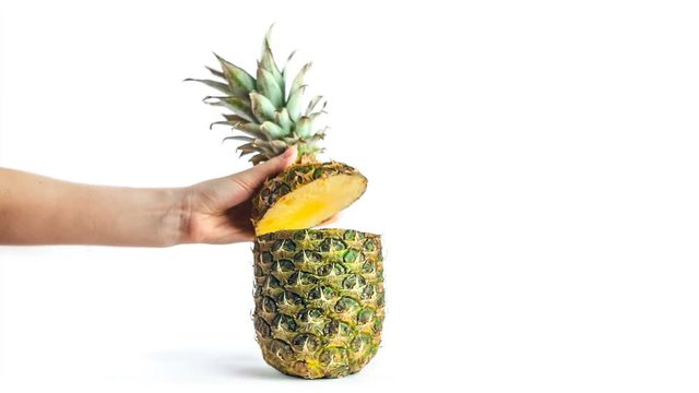 Girl's hand opens the top of a pineapple