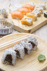 Different Sushi rolls,wasabi and ginger on a plate on wooden bac