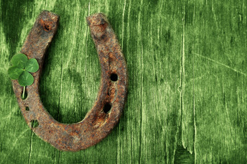 St. Patricks day, old horse shoe with clover leaf on green wooden background