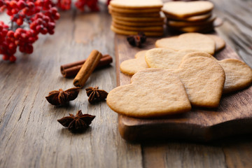 Heart shaped biscuits on cutting board with ash berry and cinnamon on wooden background