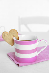 Heart shape cookie on cup of coffee on table closeup