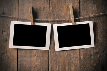 Fototapeta premium Blank Old Photo Frame Hanging on a Rope By Clothespin on.Wood Ba