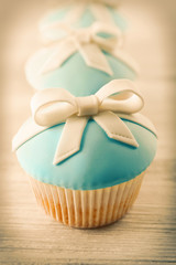 Tasty cupcakes with bow on light background