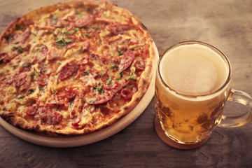 Tasty pizza and glass of beer are on wooden table, close up