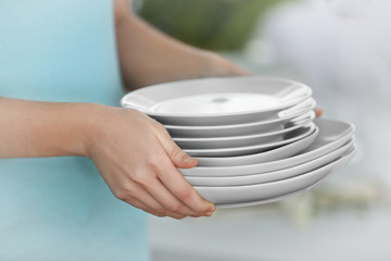 Woman holding stack of clean plates, close up