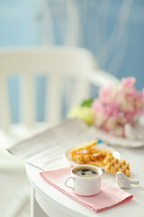 Fototapeta na wymiar Cup of coffee with wafers on white table in light interior