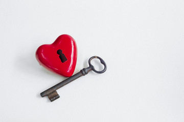 Red heart with lock next to an old key on isolated background
