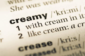 Close up of old English dictionary page with word creamy