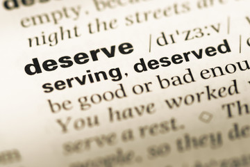 Close up of old English dictionary page with word deserve