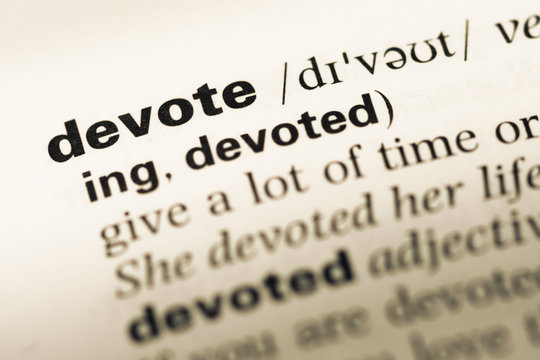 Close up of old English dictionary page with word devote