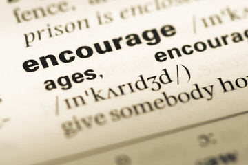Obraz premium Close up of old English dictionary page with word encourage
