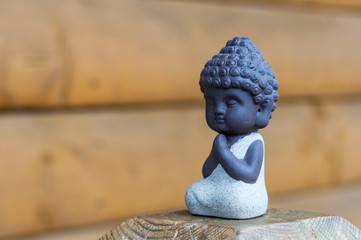 Little Buddha pray or meditate on wooden background with empty space. Praying and meditation, yoga concept
