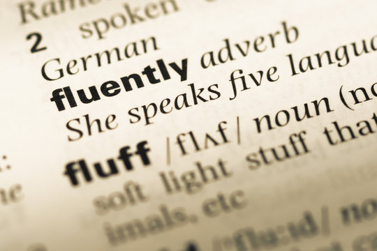 Close up of old English dictionary page with word fluently