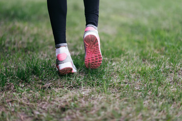 Runner feet running on road closeup on shoe. woman fitness jog workout welness concept.