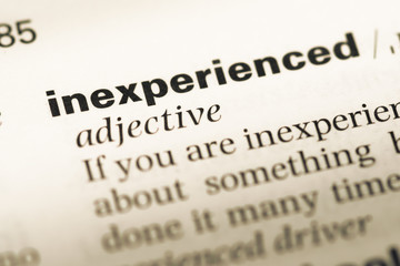 Close up of old English dictionary page with word inexperienced