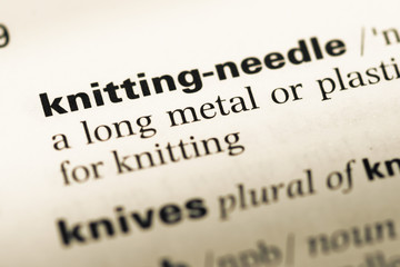 Close up of old English dictionary page with word knitting needl