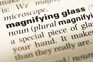 Fototapeta premium Close up of old English dictionary page with word magnifying gla