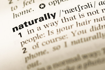 Close up of old English dictionary page with word naturally