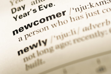 Close up of old English dictionary page with word new comer