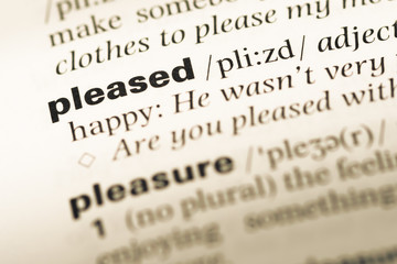 Fototapeta premium Close up of old English dictionary page with word pleased