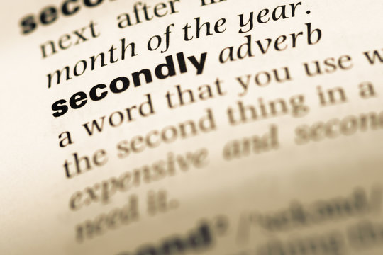Close up of old English dictionary page with word secondly