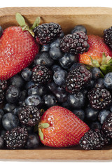 assorted berry fruits on a wooden bowl