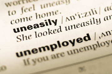 Obraz premium Close up of old English dictionary page with word uneasily