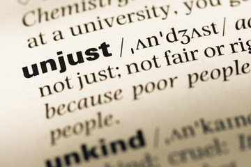 Close up of old English dictionary page with word unjust